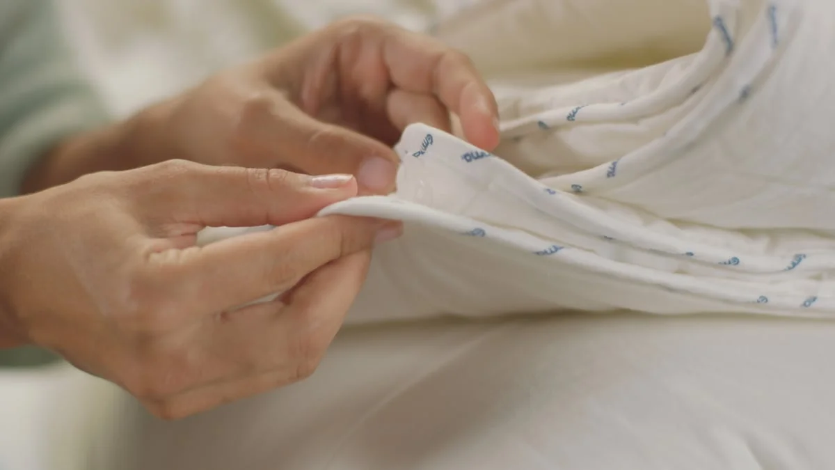 Le système d'assemblage de la Couette 4 Saisons Emma : les boutons-pression répartis sur le pourtour joignent la couette légère et la couette tempérée (visuel officiel Emma)